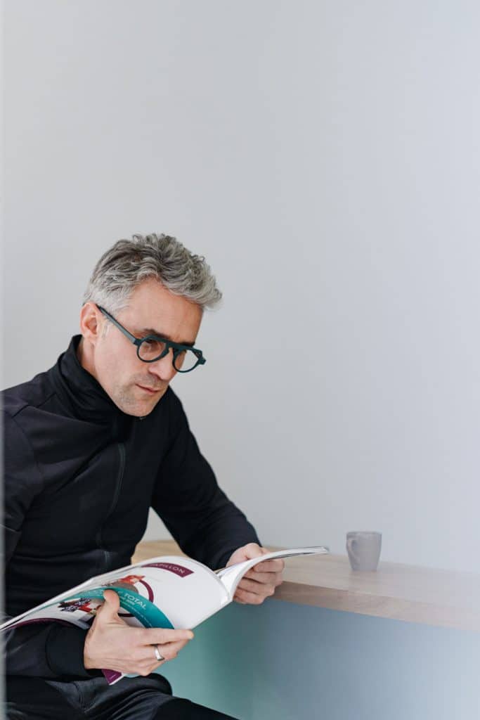 Man reading a magazine and wearing Gaston frame glasses at La Maison des Créateurs